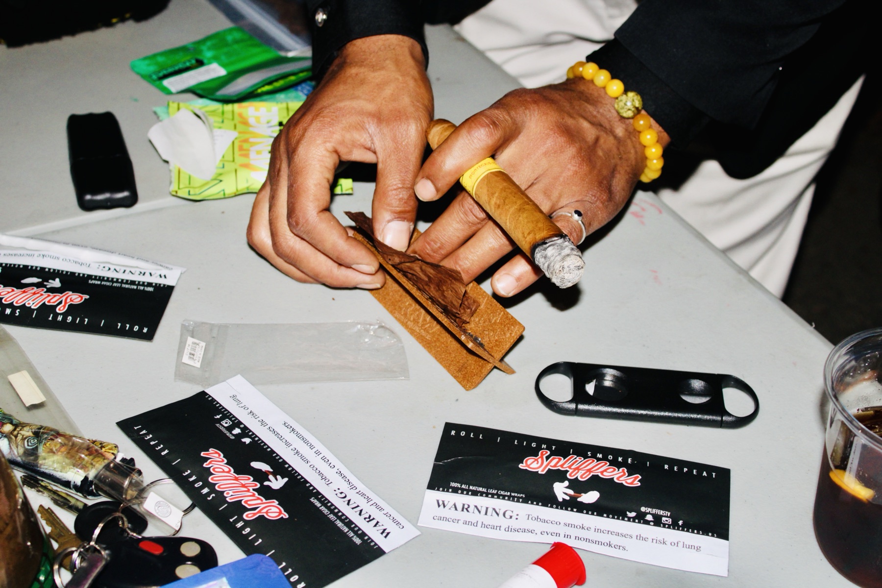 Hands preparing a wrap with Spliffers materials on the table